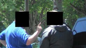 Two people with their faces obscured by a tree