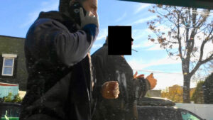 A man on the phone with his hand in his mouth.