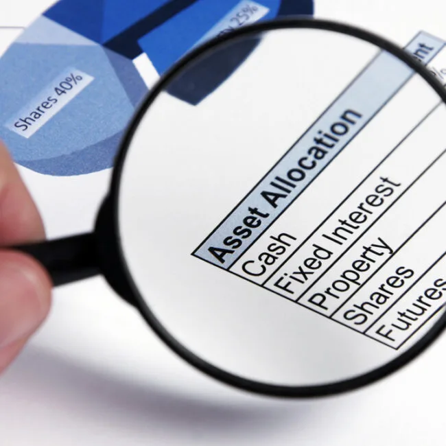 A person holding a magnifying glass over an asset allocation chart.