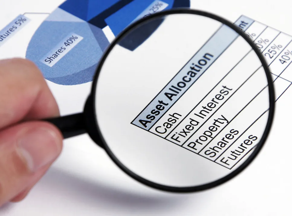 A person holding a magnifying glass over an asset allocation chart.