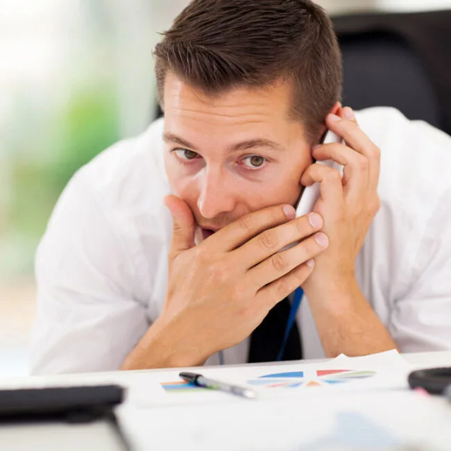 A man sitting at his desk on the phone