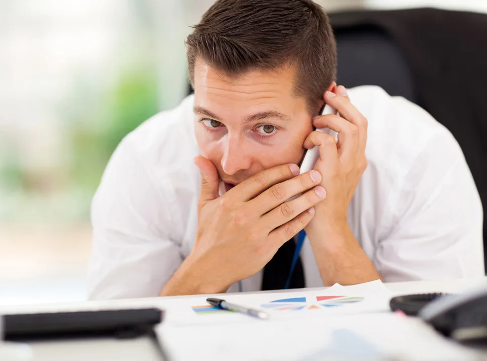 A man sitting at his desk on the phone